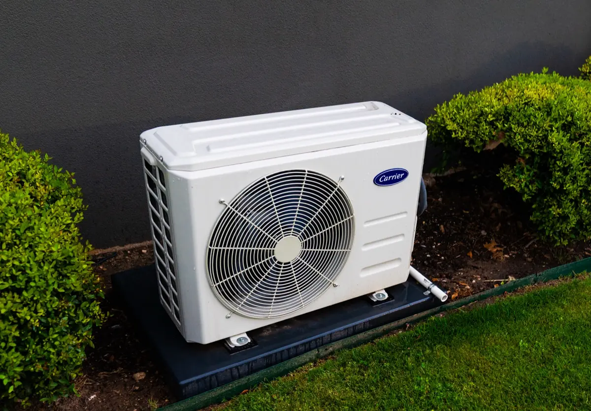 A neatly installed home heat pump unit beside a rendered wall